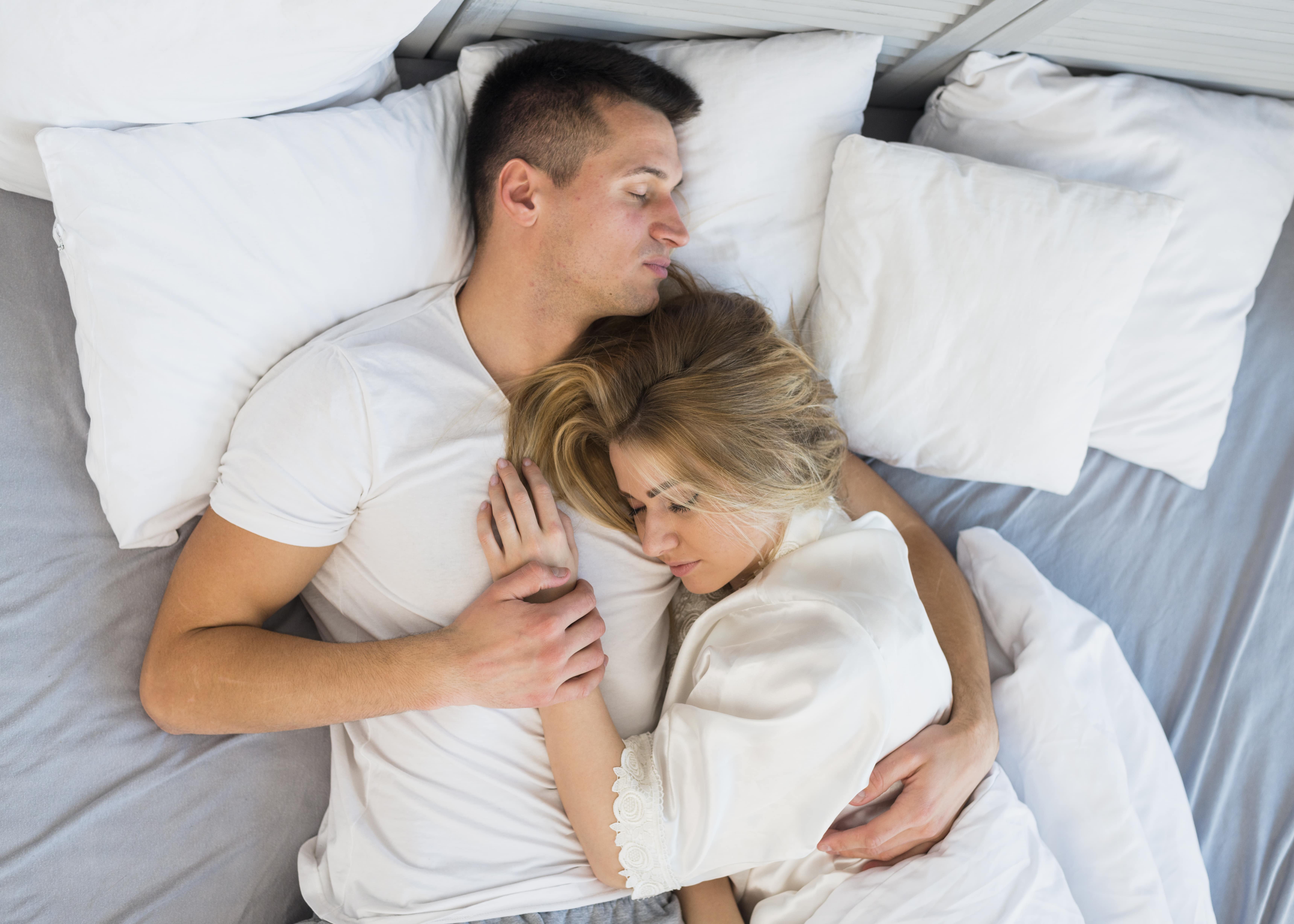 Sleeping young couple hugging on bed